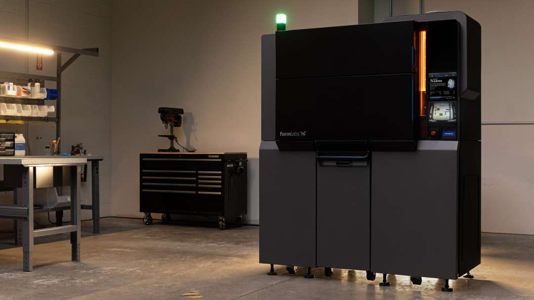 Formlabs Fuse X1 large-format industrial SLS 3D printer standing in a workshop, green status light on top, orange accent strip, active touchscreen panel