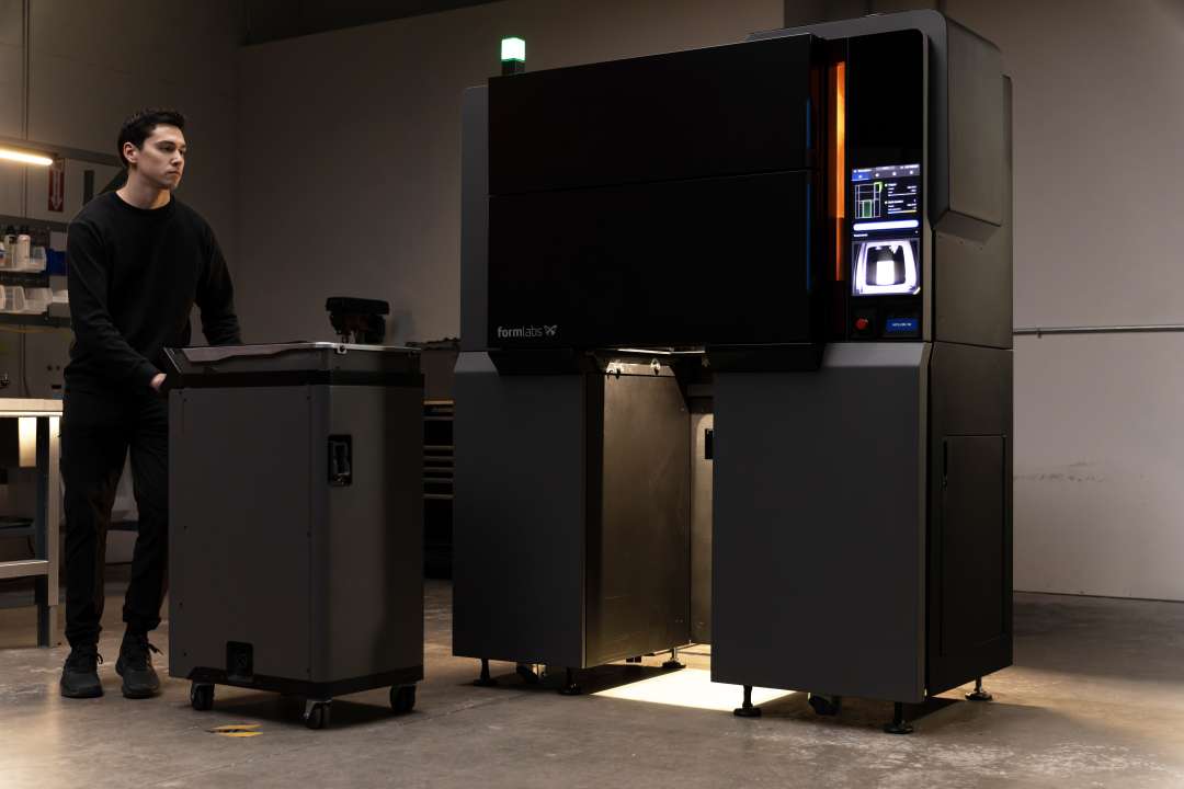Technician rolling the completed Formlabs Fuse X1 Build Unit away from the open printer bay during a rapid changeover operation