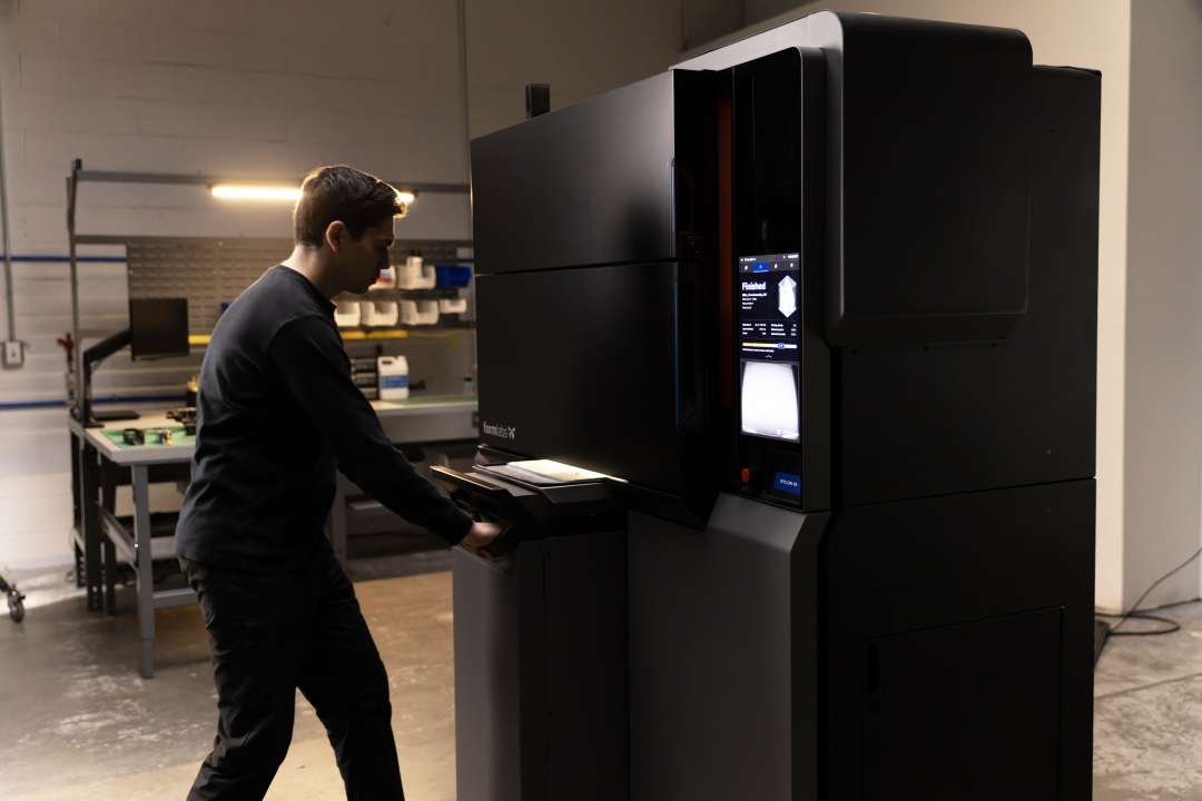 Operator inserting the Fuse X1 Build Unit into the printer bay; touchscreen displays Finished status from the preceding print job