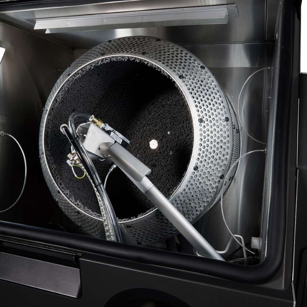 Formlabs Fuse Blast High Capacity Kit large tumbler basket fully installed inside the Fuse Blast post-processing cabinet with the automated blasting nozzle assembly in operating position