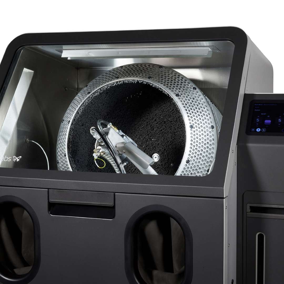 Fuse Blast machine with front access open showing Large Tumbler Basket installed inside cabinet alongside internal blasting nozzle infrastructure and Fuse Blast control panel