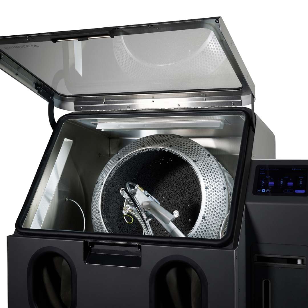 Fuse Blast machine with top lid fully open showing the Large Tumbler Basket installed inside the chamber with blasting nozzle assembly visible and Fuse Blast touchscreen panel on the right