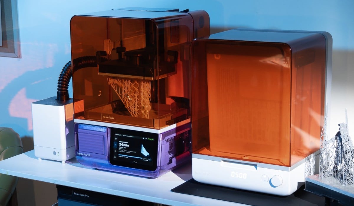 Formlabs VOC Extractor system with an air hose next to a Formlabs photopolymer 3D printer and post-processing equipment