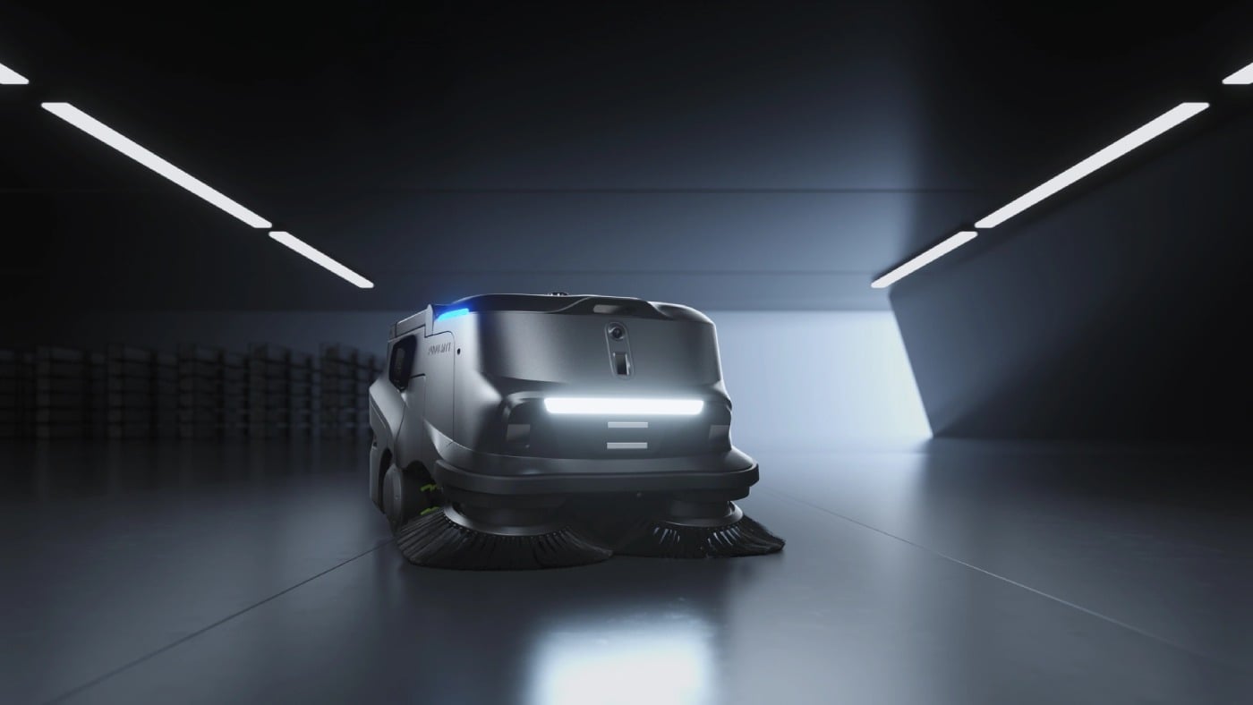 Vorderansicht des PUDU MT1 Roboterkehrers mit Seitenbürsten und LED-Lichtpanel in einem dunklen Lagergang