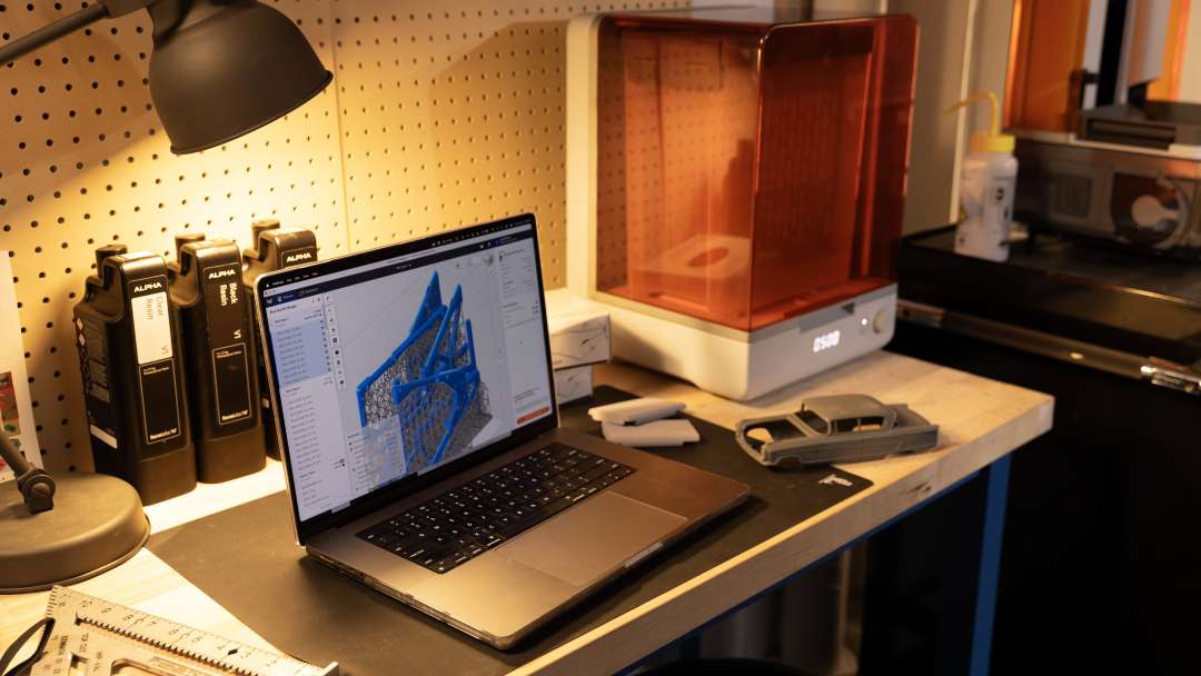 Formlabs Form Studio 1 Basic Graphite neben Harzkartuschen und einem gedruckten Automodell